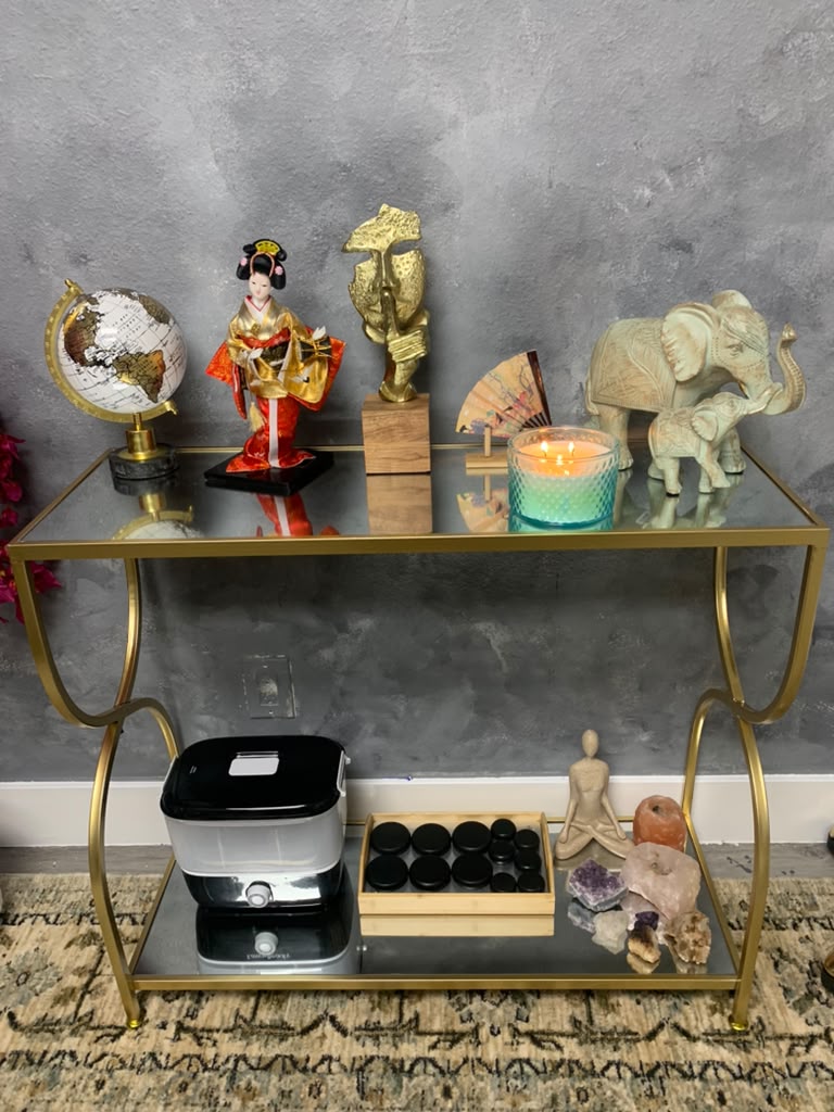 Spa ritual table with heated massage stones, a lit candle, crystals and a foot bath at Paradise Within